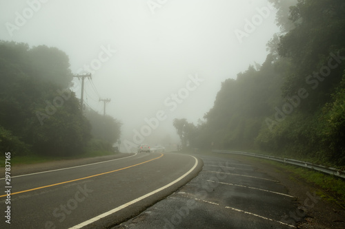 A mountain road covered by fog causing limited visibility