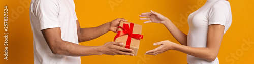 Black millennial man giving gift box to woman, panorama