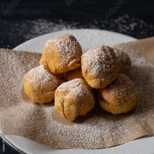 Spanish fritter dusted with sugar also called "buñuelos" on dark background