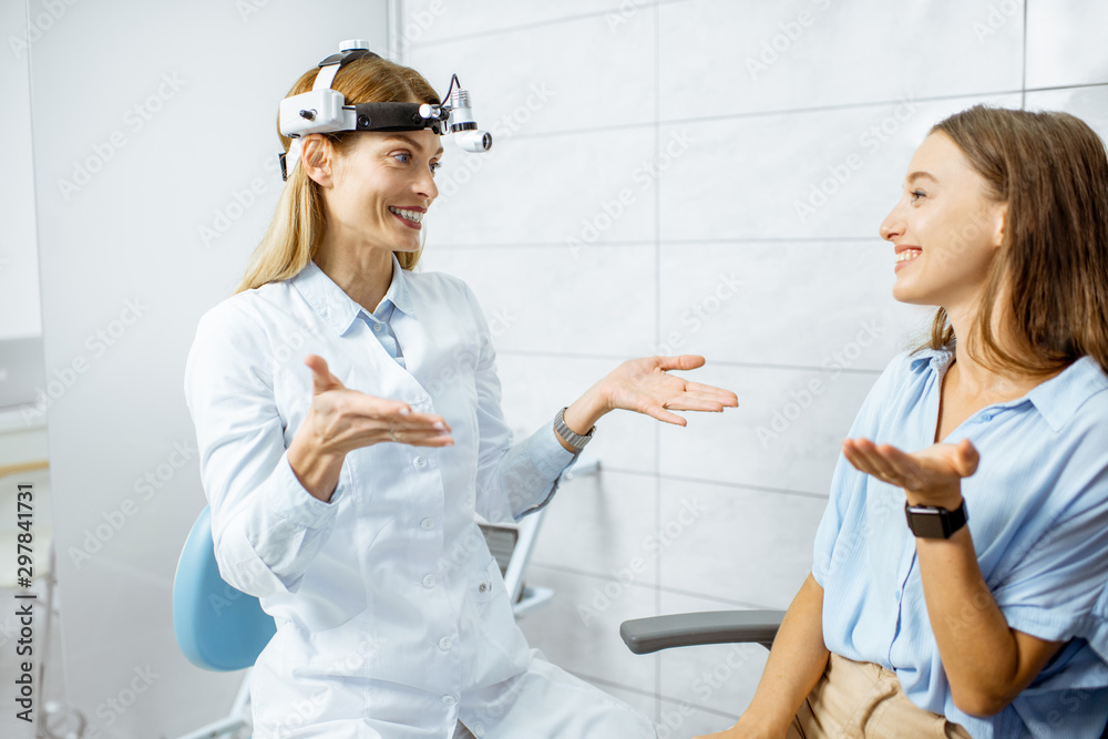 Obraz premium Happy female otolaryngologist during a medical consultation with a young patient talking in the ENT office