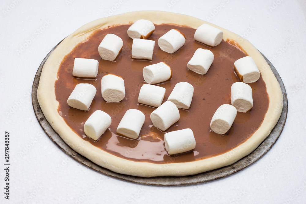 Pizza. Raw dough. Sweet pieces of pizza with murshmello and nutella. Taste piece. Top view. Black and white backgrond. Pizza. Raw dough. Sweet pieces of pizza with murshmello and nutella. Taste piece. Top view. Black and white backgrond.