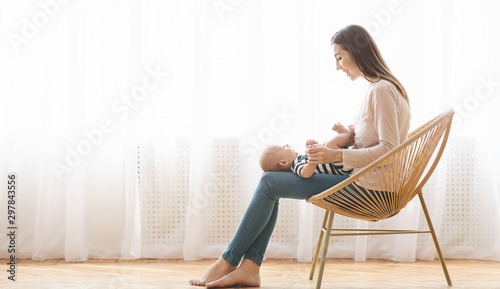 Mother sitting in wicker chair holding newborn baby on lap