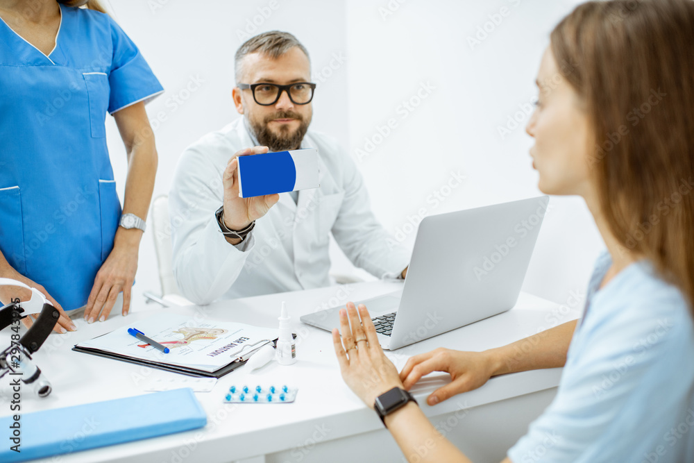 Senior doctor offering some medicine for a young patient, holding box with blank space to copy paste in the medical office Senior doctor offering some medicine for a young patient, holding box with blank space to copy paste in the medical office