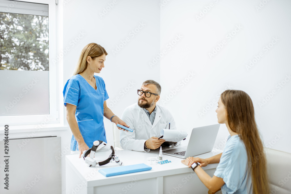 Young patient at an appointment with otolaryngologists, sitting during the consultation in the bright ENT office interior Young patient at an appointment with otolaryngologists, sitting during the consultation in the bright ENT office interior