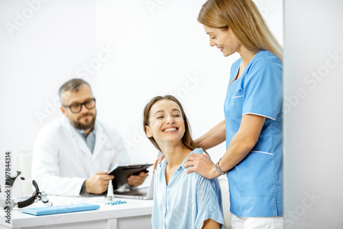 Nurse supporting young patient during a medical consultation with senior doctor in the white office