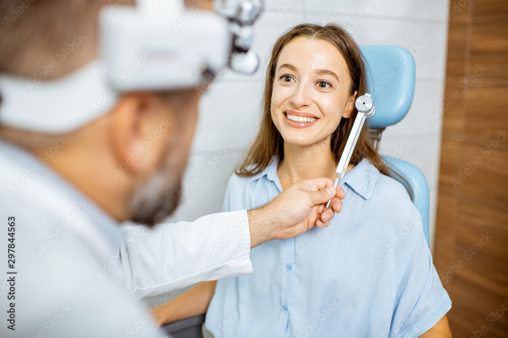 Senior otolaryngologist examining ears with ENT tuning fork for a young