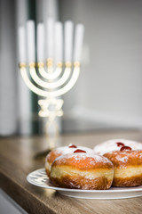 Jewish Hanukkah menorah and sufganiyot donuts on wooden table