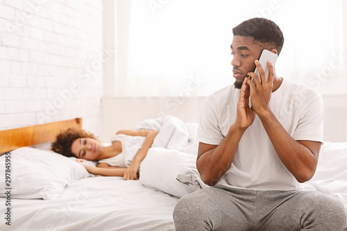 Fotografija African man talking with mistress at home, hiding from his wife