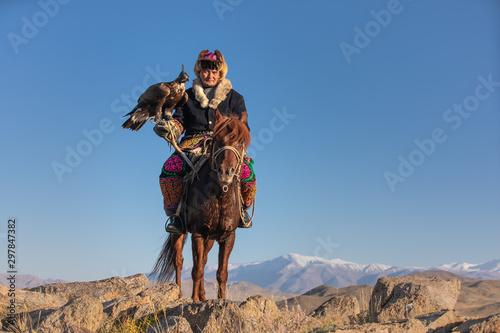 Old traditional kazakh eagle hunter posing with his golden eagle in the mountains. Ulgii  Western Mongolia.