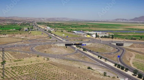 Road junction with four way and bridge among agriculture landscape and mountains with dry rocky ground / Aerial drone view photo