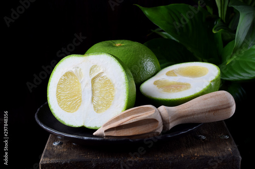 Sweetie cut into halves on a stone plate on the edge of the wooden table against black background