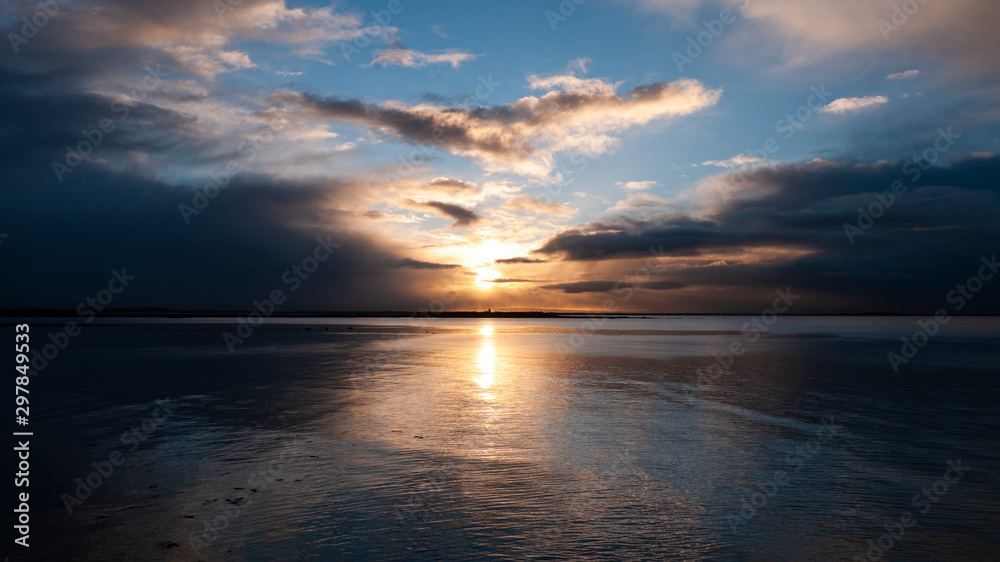 Stunningly beautiful sunrise, taken on a cloudy morning from Salthill beach near Galway, Ireland. Showing the calm water of Galway Bay and Mutton Island in the distance.