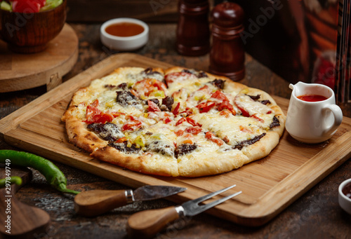 meat pizza with vegetables and cheese on wooden board