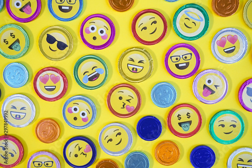 Chocolate coins. Top view photo of chocolate coins with various expressions, pop art style, on a yellow background.