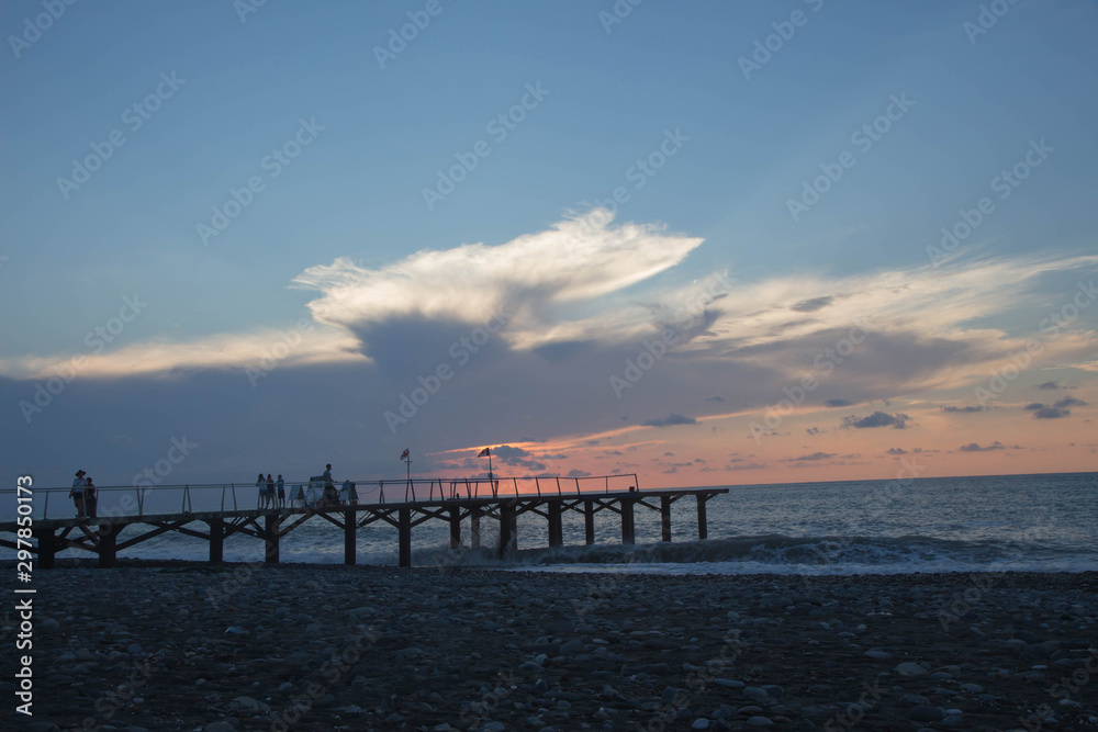 over Batumi beach Jetty, as powerful waves roll in, and a very colorful sky is reflected on the beach. sunset on the city embankment