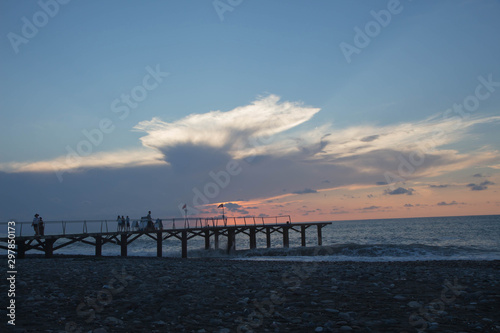 over Batumi beach Jetty  as powerful waves roll in  and a very colorful sky is reflected on the beach. sunset on the city embankment