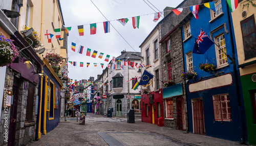 View of the main high street in Galway City with the brightly painted buildings and cobblestone streets on a cloudy day