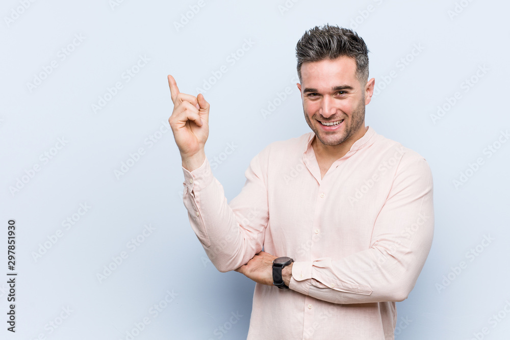 Young handsome cool man smiling cheerfully pointing with forefinger away. Young handsome cool man smiling cheerfully pointing with forefinger away.