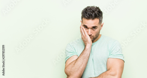 Young handsome man against a green background who is bored, fatigued and need a relax day.