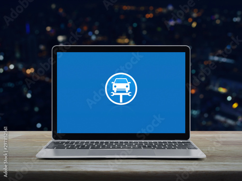 Service fix car with wrench tool flat icon on modern laptop computer on wooden table over blur colorful night light office city tower and skyscraper, Business repair car online concept