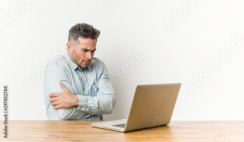 Young handsome man working with his laptop going cold due to low temperature or a sickness.