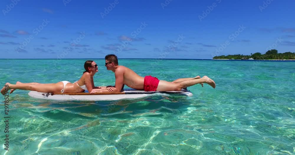 Just married couple paddling on a swimming board on emerald clean water near Solomon Islands Just married couple paddling on a swimming board on emerald clean water near Solomon Islands