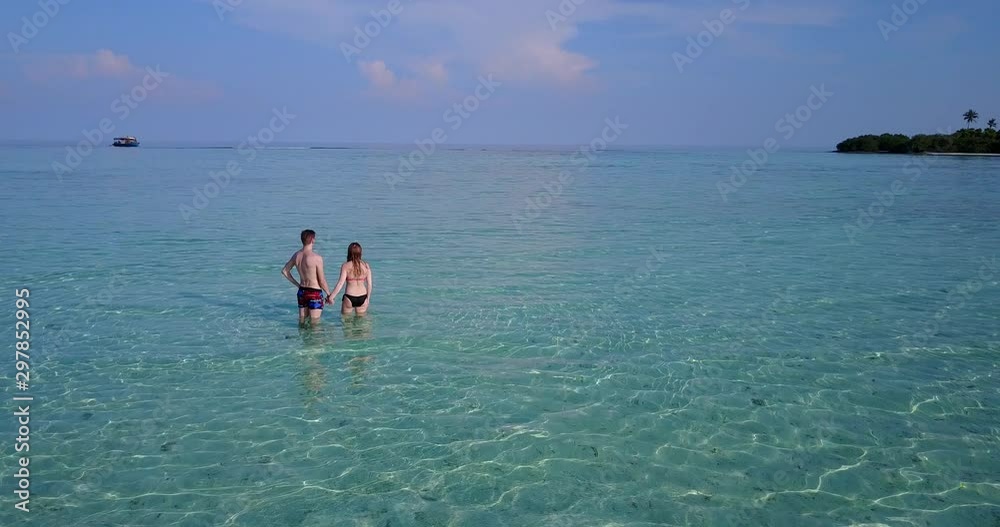 Caucasian couple on shallow crystal water of Masalembu Islands, enjoying a beach vacation Caucasian couple on shallow crystal water of Masalembu Islands, enjoying a beach vacation