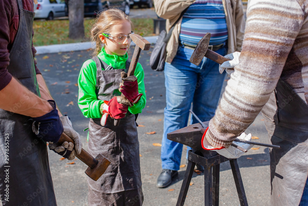 Obraz premium A blacksmith forges a metal blank on the anvil at a fair in the presence of spectators.