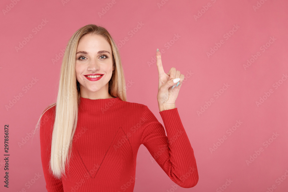 Young happy model pointing up by finger isolated over the pink background
