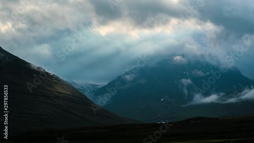 Time lapse, sun rays through moody clouds over mountains in east iceland