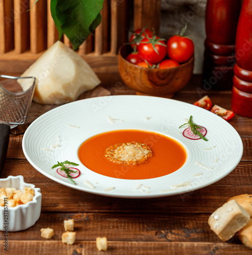 plate of tomato soup garnished with grated parmesan in soup bowl