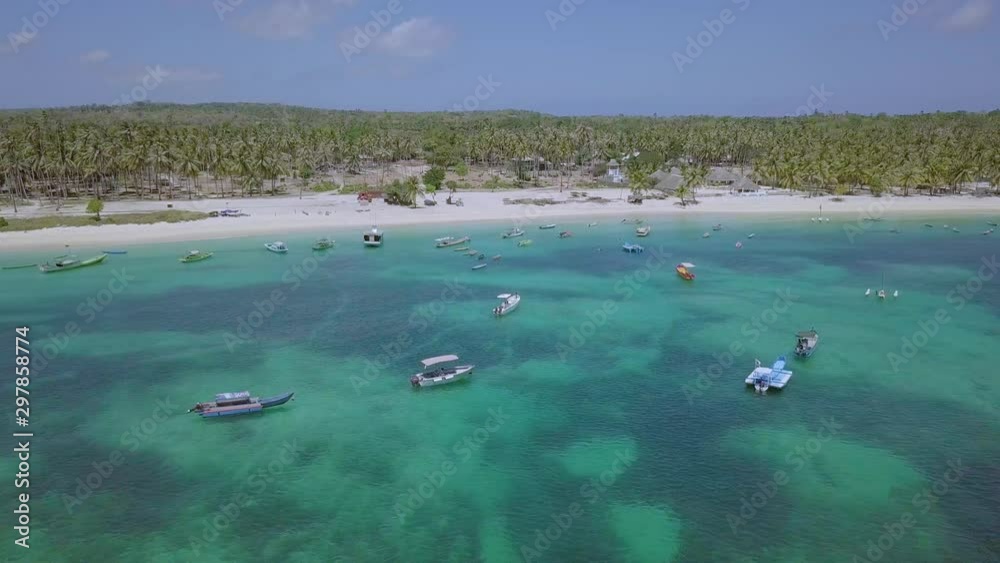 Birds eye view showing the blue waters with fisherman boats and dense greenery on the beaches of Rote islands,Indonesia.Backward moving aerial drone footage.(1) Birds eye view showing the blue waters with fisherman boats and dense greenery on the beaches of Rote islands,Indonesia.Backward moving aerial drone footage.(1)