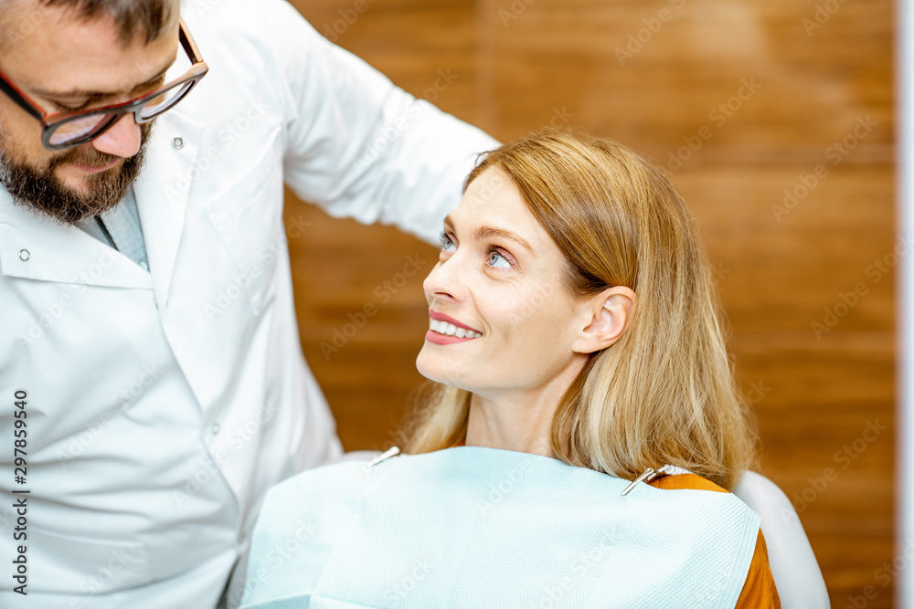 Fototapeta premium Beautiful woman as a patient with senior dentist smiling and feeling trust during a medical consultation at the dental office