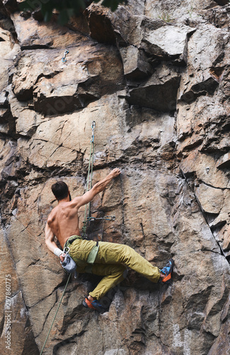 Fototapeta Naklejka Na Ścianę i Meble -  strong muscular man rockclimber climbing on tough sport route, resting and chalking hands.