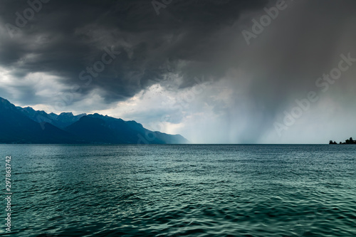 Landscape of Alps mountains,lake Geneva,cloudy dark sky with rain in the distance. Shot taken from the shore of the lake in Montreux, Switzerland.  © mimpki