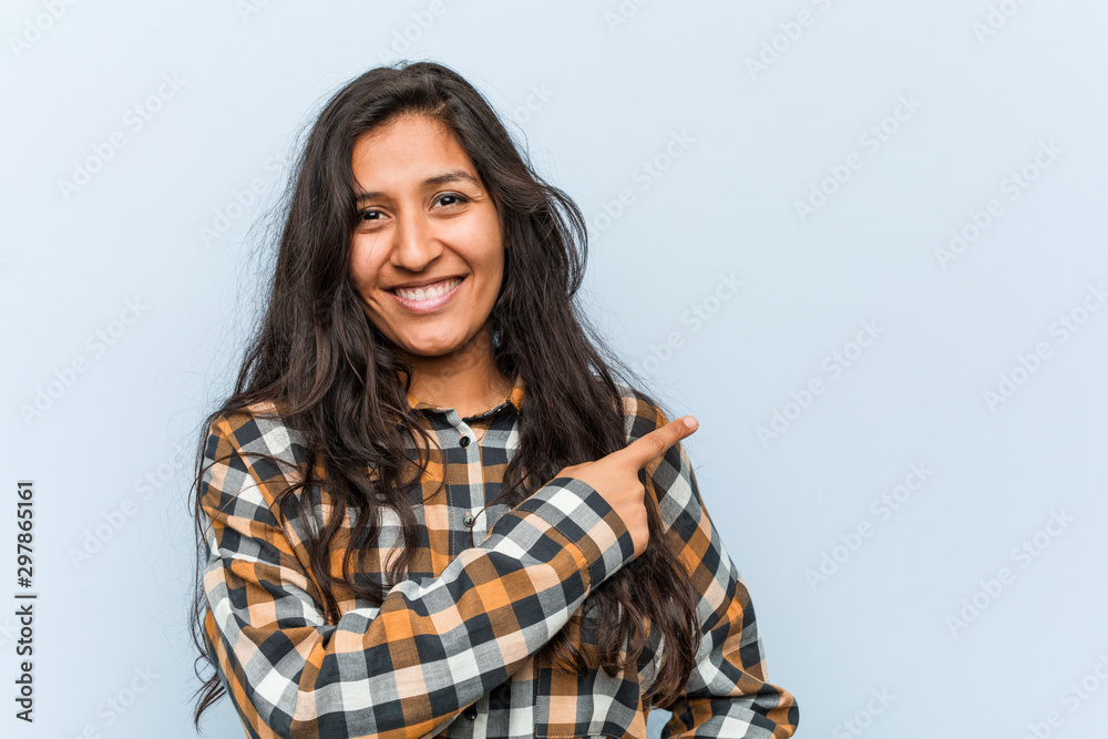 Young cool indian woman smiling and pointing aside, showing something at blank space. Young cool indian woman smiling and pointing aside, showing something at blank space.