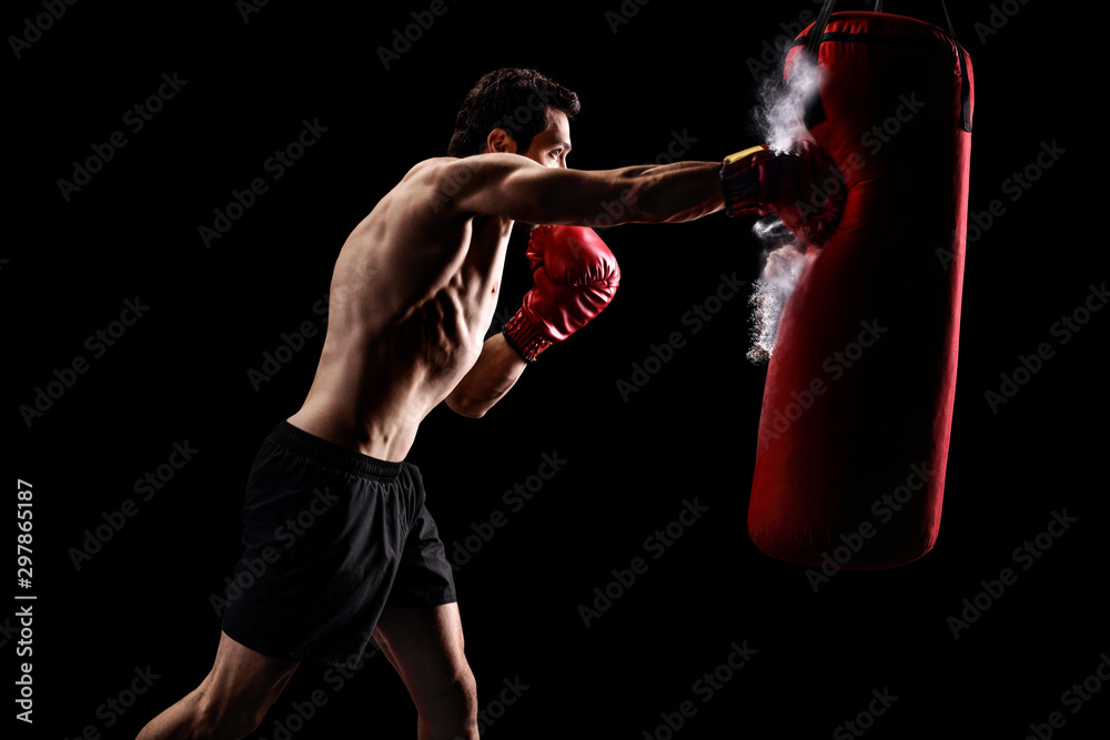 Strong man punching a bag on a black background