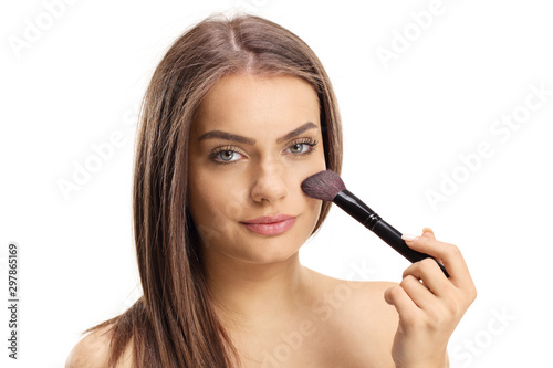 Close up of a beautiful young girl applying make up with a brush