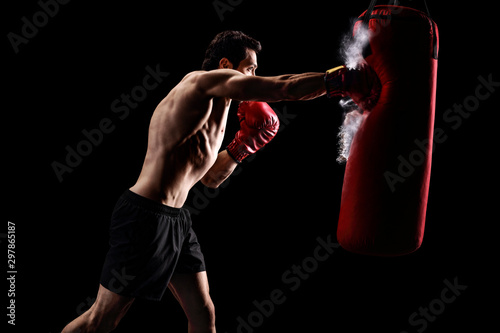 Strong man punching a bag on a black background