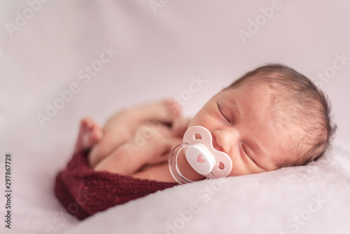 newborn baby with pacifier tucked in a ball of wool. Newborn session concept