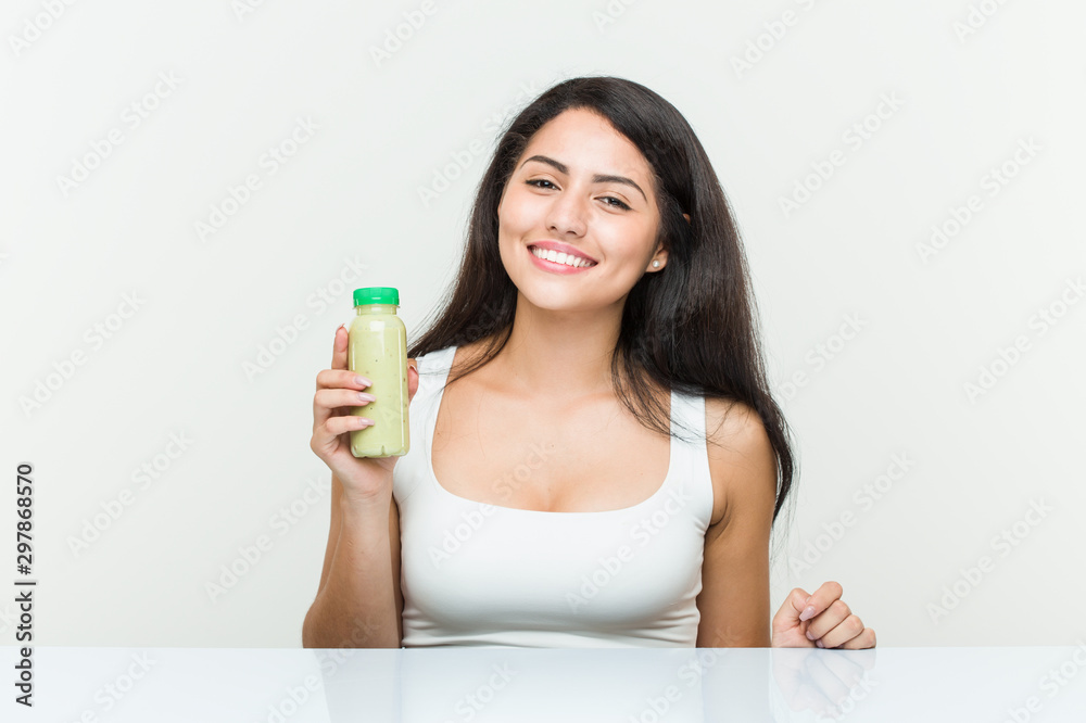 Young hispanic woman holding a vegetable drink happy, smiling and cheerful. Young hispanic woman holding a vegetable drink happy, smiling and cheerful.