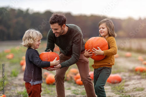 Obraz na płótnie Father and sons in pumpkin patch field