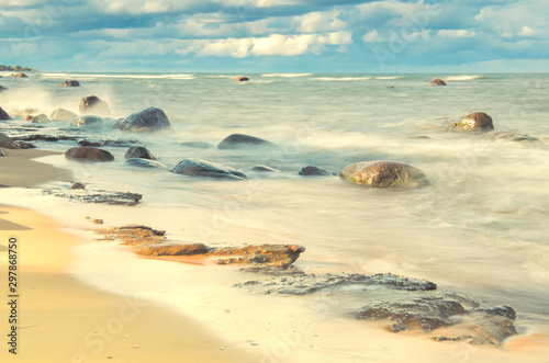 Long Exposure of the Baltic sea landscape. White sand, stones, waves and blue sky. Pakri Peninsula, Harju County, Estonia.