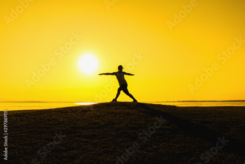Silhouette of a runner who exercises with nature on the lake at sunrise.
