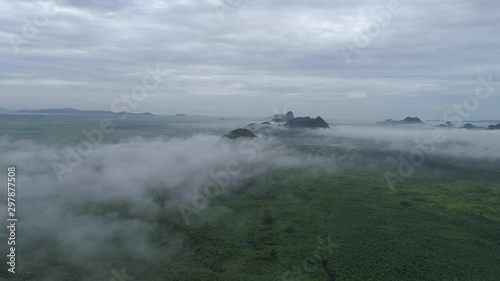 Aerial footage of flight over the plains of Padang Besar in Perlis, Malaysia with beautiful limestone hills rising majestically from the flat landscape through low hanging clouds. photo