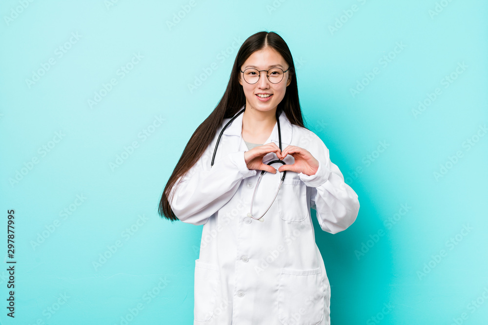 Young chinese doctor woman smiling and showing a heart shape with hands. Young chinese doctor woman smiling and showing a heart shape with hands.