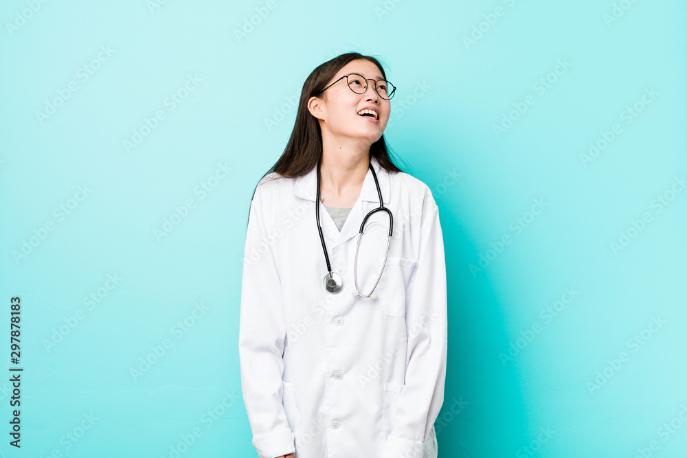 Young chinese doctor woman relaxed and happy laughing, neck stretched showing teeth.