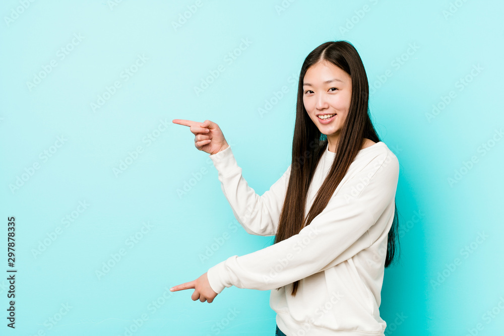 Young pretty chinese woman excited pointing with forefingers away. Young pretty chinese woman excited pointing with forefingers away.