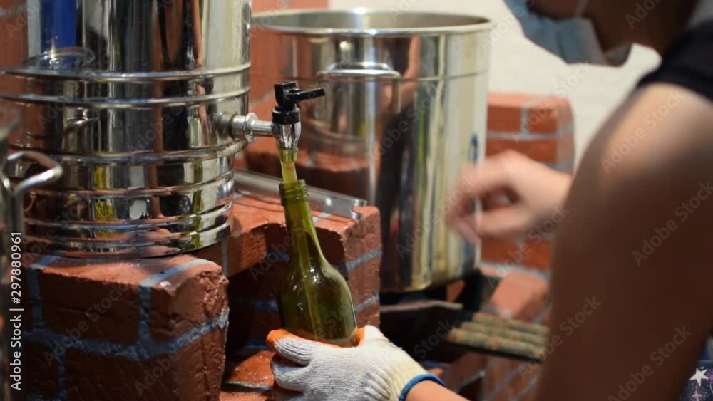 Woman pouring fermented alcoholic juice in wine bottle in a home based winery. close up