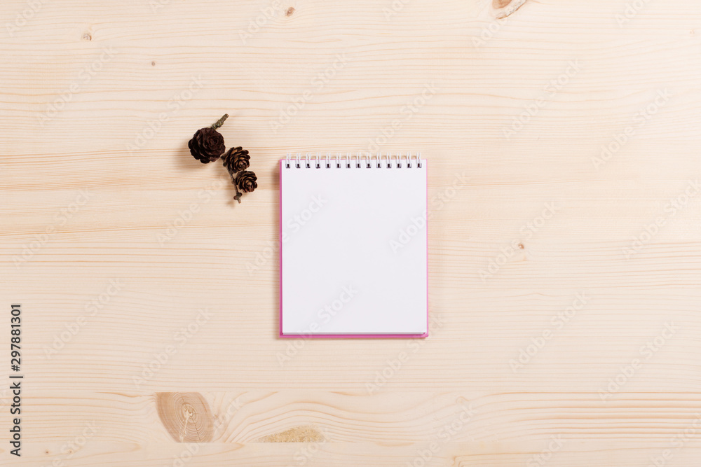 Spiral blank notepad and three brown pinecones on wooden background. Top view, place for text. Spiral blank notepad and three brown pinecones on wooden background. Top view, place for text.